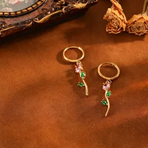 Detailed view of elegant gold tulip hoop earrings with pink and green crystal flower petals