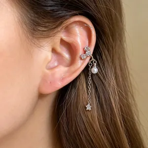 Close-up of a silver zircon ear cuff with a dangling pearl star on a model's ear