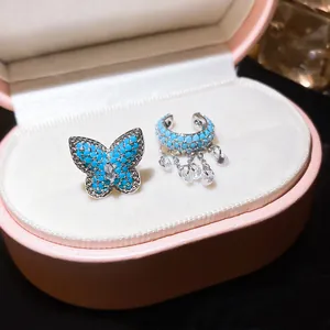 Detailed view of blue butterfly and zircon ear bone clips inside a pink jewelry box.