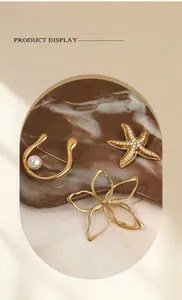 Detail view of gold-plated starfish, flower, and pearl brooches set on marble stone
