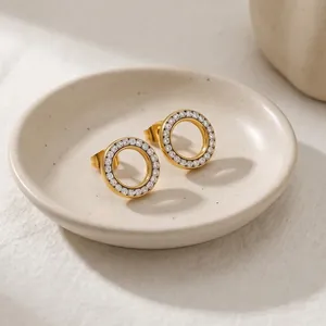 Elegante gouden holle ronde oorknopjes met kristallen op een keramische schaal