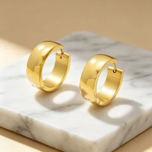 Close-up macro view of gold minimalist stainless steel chunky hoop earrings on marble