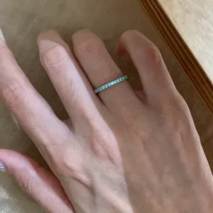 Close-up detail of a minimalist slim silver ring with light blue eternity stones.