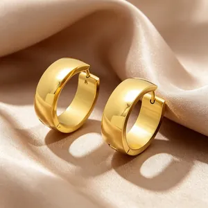 Close-up of minimalist gold-plated stainless steel hoop earrings on silk background.