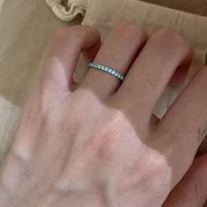 Detailed close-up of a minimalist ring with sparkling light blue gemstones on hand.
