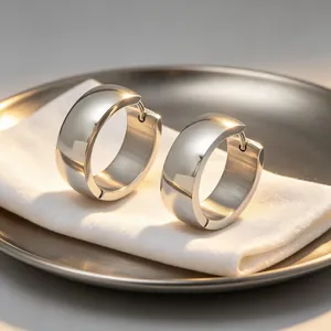 Detailed view of polished silver stainless steel wide hoop earrings on a display tray.