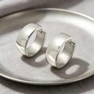 Close-up of polished stainless steel hoop earrings with a wide, minimalist design.
