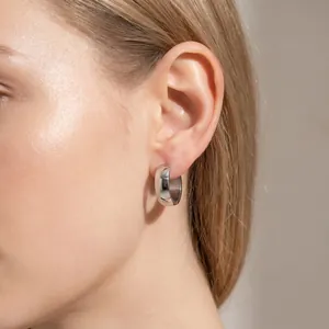 Detailed close-up showing a minimalist silver stainless steel chunky hoop earring on ear