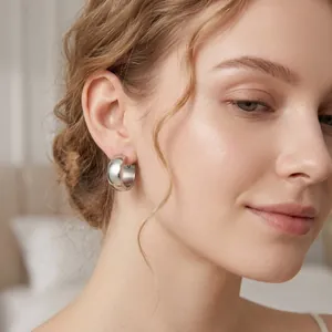 Close-up of simple polished silver stainless steel hoop earring on female model