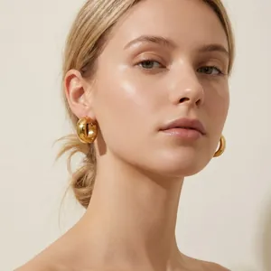 Close-up of a model wearing minimalist gold-plated stainless steel chunky hoop earrings.