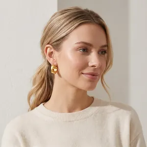 Close-up view of minimalist gold-plated stainless steel hoop earring worn by a model