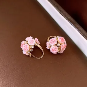 Elegante goldfarbene Creolen mit zarten rosa Harzrosen und funkelnden Strasssteinen