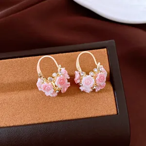 Detailansicht goldener Creolen mit rosa Harzrosen und funkelnden Strasssteinen