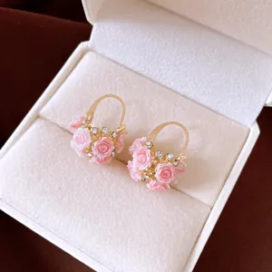 Detailansicht exquisiter vergoldeter Korbohrringe mit rosa Harzrosen und kleinen Strasssteinen
