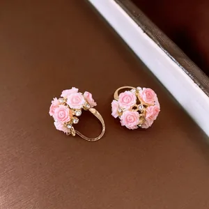 Nahaufnahme von Vintage-Creolen mit rosa Resinn-Blumen und kleinen klaren Strasssteinen.