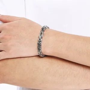 Classic silver stainless steel Byzantine chain bracelet worn on a male wrist detail view