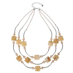 Detail view of a sophisticated three-layer beaded necklace featuring square amber marbled beads