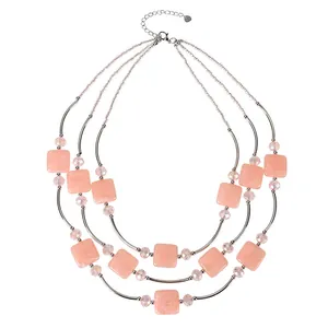 Close-up of elegant three-layered necklace with pink square beads and silver tubes