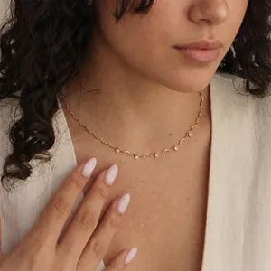 Detailweergave van een gegolfde gouden roestvrijstalen ketting met zirkonia op model.