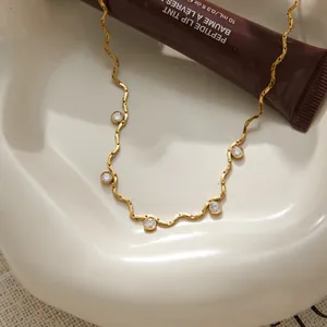 Detail van een gouden titanium stalen ketting met vijf fonkelende zirkonia's.