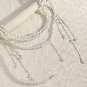 Close-up of elegant multi-layered white pearl body chain featuring silver tassel dangles
