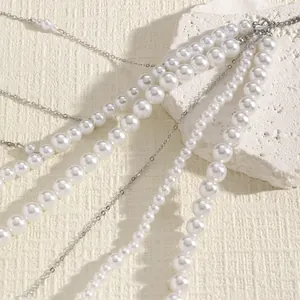 Detailed view of elegant multi-layered white pearl and silver chain body accessory