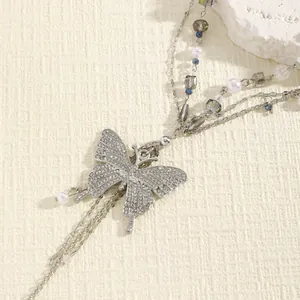 Close-up of elegant silver butterfly pendant on multi-layer pearl waist chain for dresses.