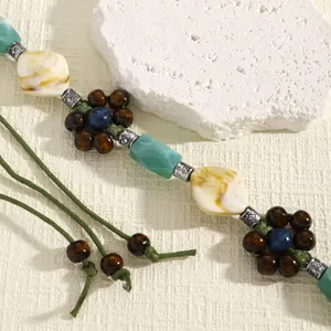 Detail of boho waist chain with green cord, wooden flower beads and resin accents