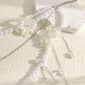 Detailed view of multi-layer white pearl body chain with delicate resin flower pendants.