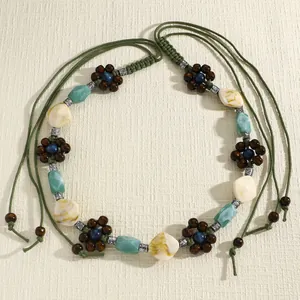 Close-up detail of bohemian braided waist chain featuring wooden floral accents