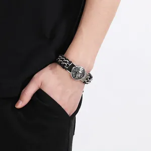 Close-up of a men's black braided leather bracelet with a silver lion head centerpiece.