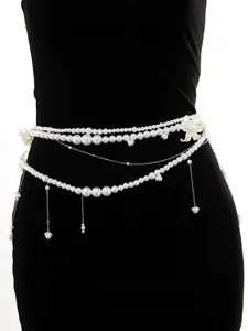 Resort style multi-layered pearl waist chain with shell floral pendants on black dress