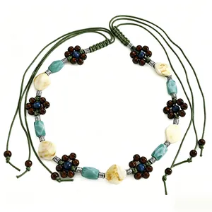 Detailed macro view of bohemian woven waist chain with turquoise and cream resin beads.