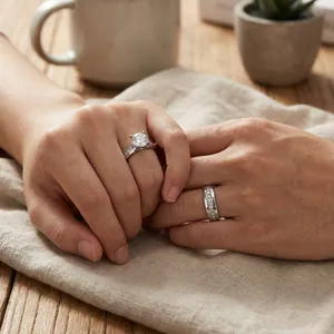 Couple's stainless steel wedding rings shown on hands in a warm lifestyle setting.