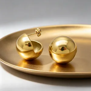 Detailed macro view of gold-plated stainless steel ball earrings with mirror finish