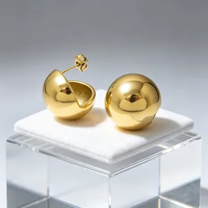 Macro view of gold-tone polished semi-spherical and round stud earrings on a display pad