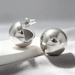 Close-up of shiny stainless steel spherical stud earrings with mirror finish