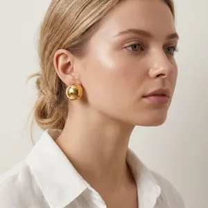 Elegant gold-finish stainless steel hemispherical ball stud earrings on model.