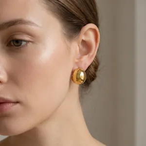 Close-up detail of minimalist gold-finished stainless steel semi-sphere dome earrings
