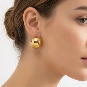 Detail view of gold polished semi-sphere stud earrings on model for a chunky minimalist style