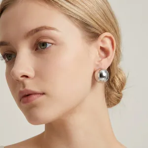 Close-up detail of a polished silver hemispherical stud earring on a female model.