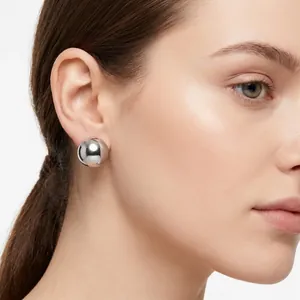 Close-up of minimalist silver stainless steel semi-spherical stud earring on model's ear
