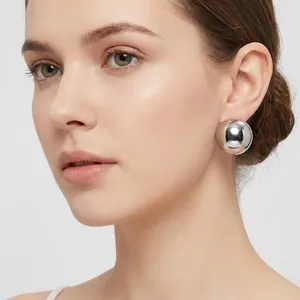 Close-up detail of a minimalist large silver polished ball stud earring on model's ear
