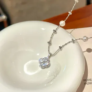 Close-up of a sparkling silver zircon flower pendant on a dainty pearl beaded necklace