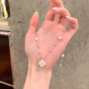 Close-up view of an elegant silver flower pendant necklace with pearls shown in hand