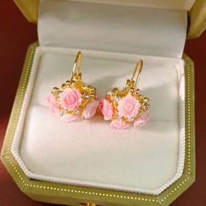 Detailed view of pink resin rose flower basket earrings with rhinestones in a jewelry box