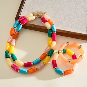Dettaglio di set collana e bracciale in perle acriliche colorate con maglie dorate