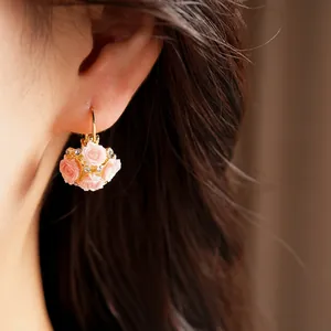 Close-up of elegant pink resin rose flower basket hoop earrings with tiny crystals