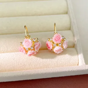 Close-up of sweet pastoral style earrings with pink resin flowers and crystals