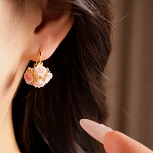Detail view of pink resin rose flower basket hoop earrings with rhinestones on ear